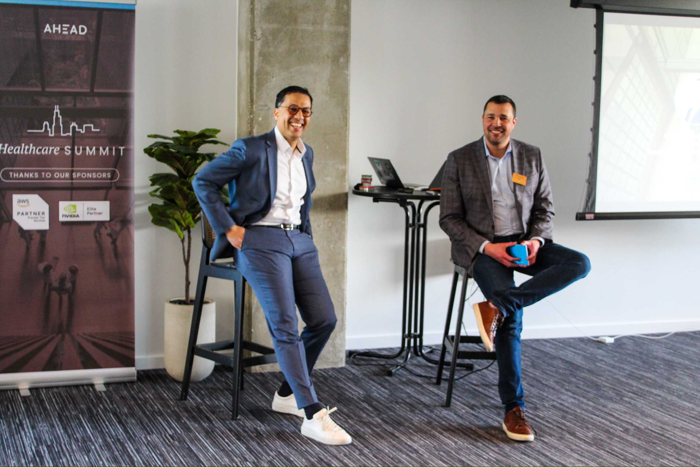 Two men sitting on stools in a conference room
