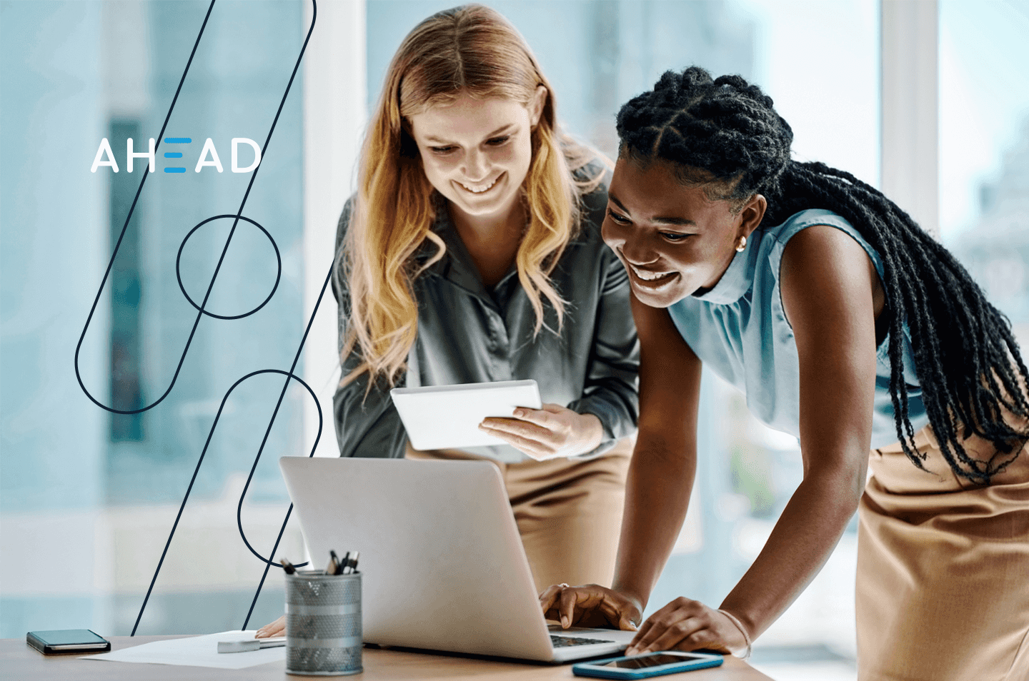 two women standing over a laptop computer
